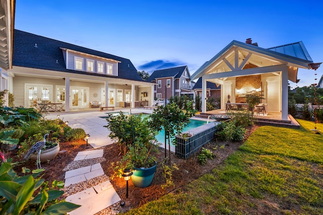 back house at dusk with a yard and a patio area