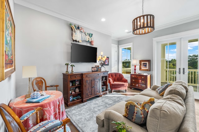 living room featuring french doors, ornamental molding, a chandelier, and hardwood / wood-style flooring