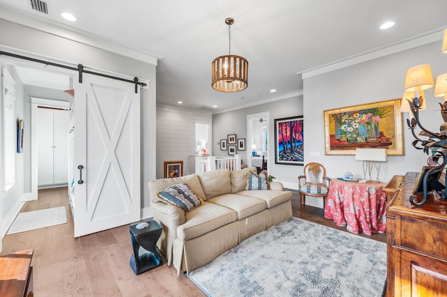 living room featuring crown molding, a barn door, a chandelier, and light hardwood / wood-style flooring