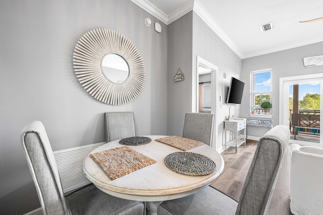 dining space featuring wood-type flooring and crown molding