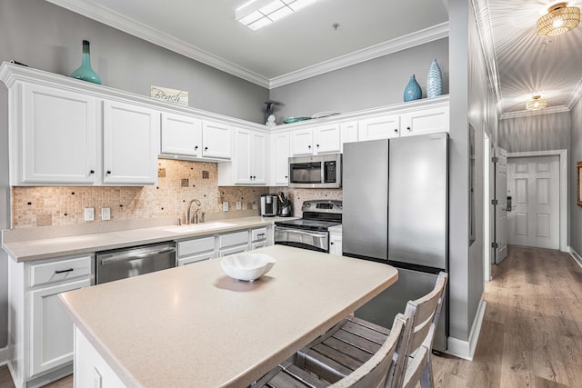 kitchen featuring sink, crown molding, decorative backsplash, white cabinets, and appliances with stainless steel finishes