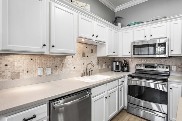 kitchen with white cabinetry, sink, stainless steel appliances, backsplash, and ornamental molding