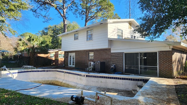 back of property with cooling unit and an empty pool