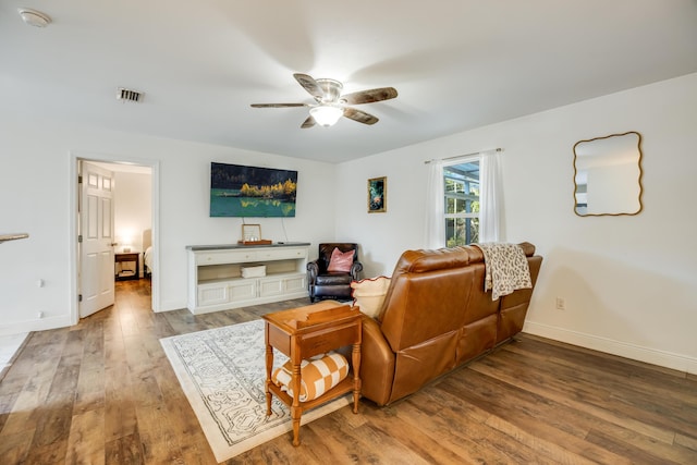 living room featuring visible vents, ceiling fan, baseboards, and wood finished floors