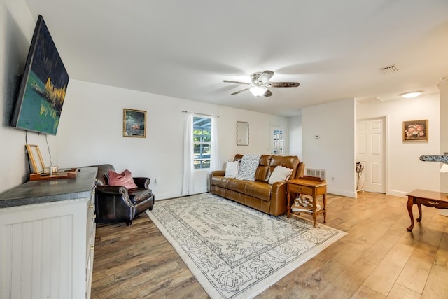 living area with ceiling fan, wood finished floors, visible vents, and baseboards