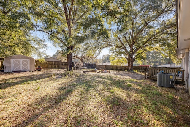 view of yard featuring a storage shed, a fenced backyard, cooling unit, and an outdoor structure