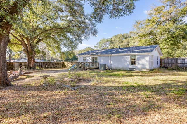 rear view of property with a fenced backyard, a yard, brick siding, and central air condition unit