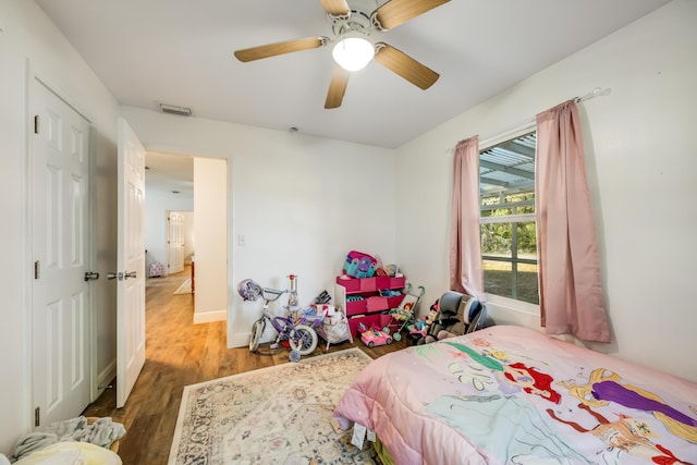 bedroom featuring wood finished floors, visible vents, baseboards, a ceiling fan, and a closet