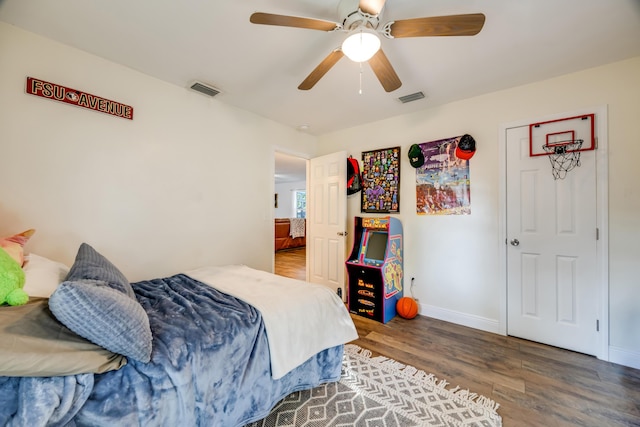 bedroom with a ceiling fan, visible vents, baseboards, and wood finished floors