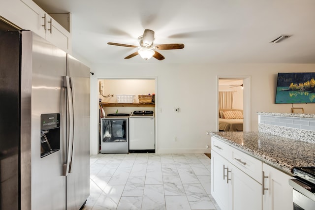 kitchen with light stone counters, marble finish floor, appliances with stainless steel finishes, washing machine and dryer, and white cabinets