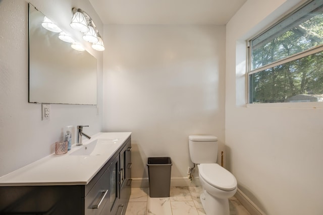 half bath featuring toilet, marble finish floor, vanity, and baseboards