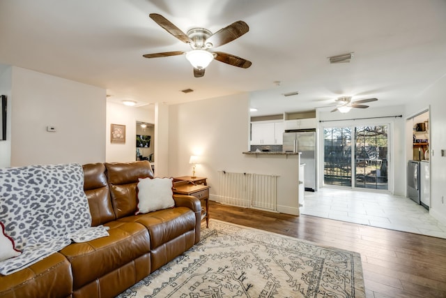 living room with ceiling fan, baseboards, visible vents, and light wood-style floors