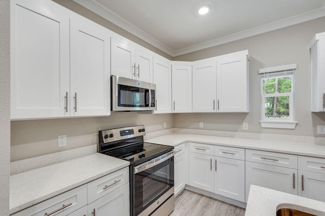 kitchen featuring white cabinets, stainless steel appliances, light hardwood / wood-style flooring, and crown molding