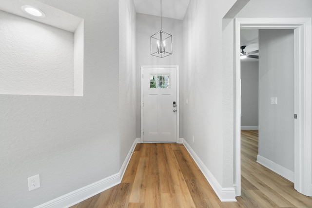 doorway featuring ceiling fan with notable chandelier and hardwood / wood-style flooring