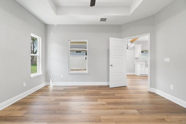 unfurnished room featuring a tray ceiling and light hardwood / wood-style flooring