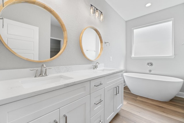 bathroom with hardwood / wood-style flooring, vanity, and a bathing tub