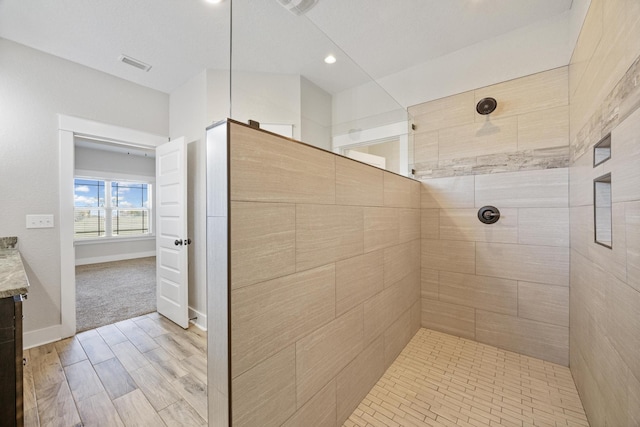 bathroom featuring a tile shower, hardwood / wood-style floors, and vanity