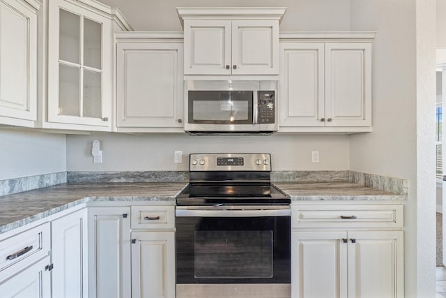 kitchen with white cabinets, stainless steel appliances, and light stone countertops