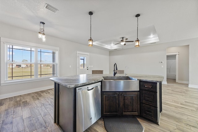 kitchen featuring dishwasher, a raised ceiling, sink, an island with sink, and light hardwood / wood-style floors