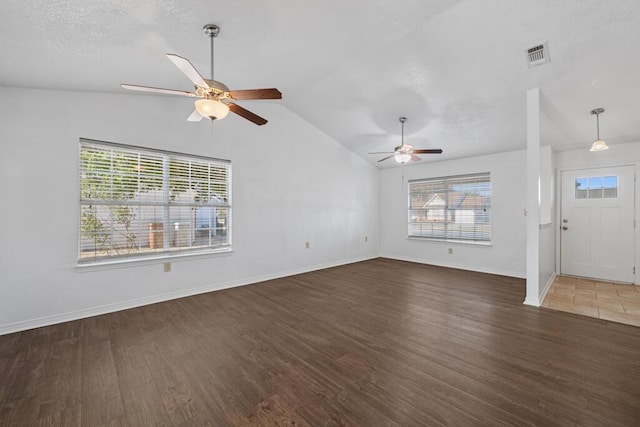 unfurnished living room featuring vaulted ceiling, ceiling fan, a healthy amount of sunlight, and dark hardwood / wood-style floors