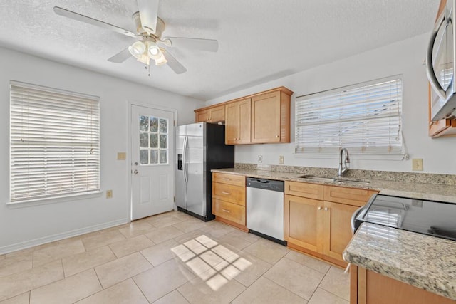 kitchen with sink, ceiling fan, light tile patterned floors, light brown cabinetry, and stainless steel appliances