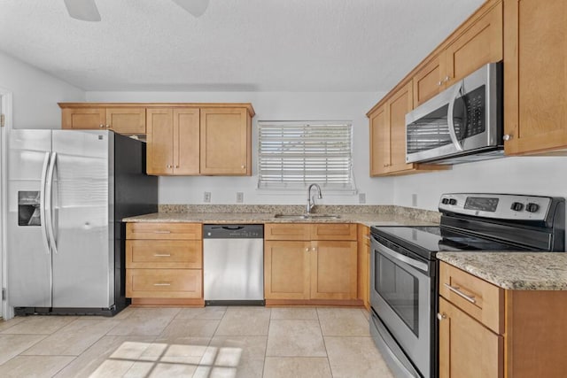 kitchen featuring light stone counters, a textured ceiling, stainless steel appliances, sink, and light tile patterned floors