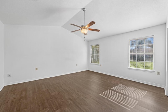 spare room with dark hardwood / wood-style floors, a wealth of natural light, and vaulted ceiling