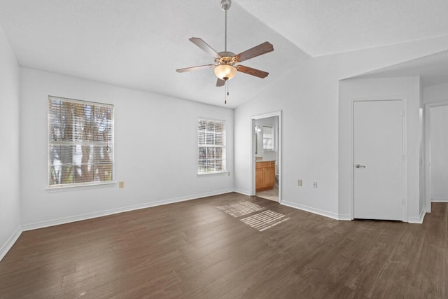 unfurnished bedroom featuring dark hardwood / wood-style flooring, vaulted ceiling, ceiling fan, and connected bathroom