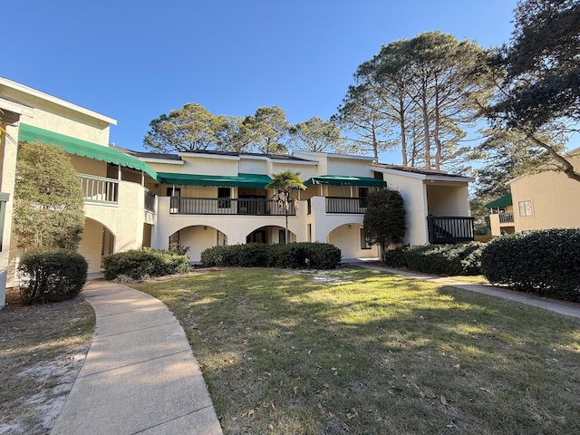 view of front of house with a balcony and a front yard