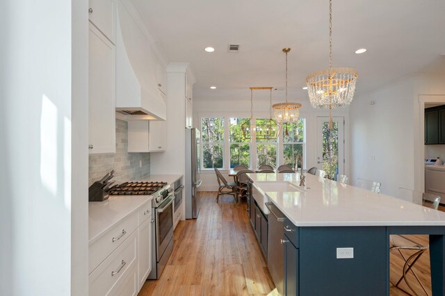 kitchen featuring a kitchen bar, stainless steel appliances, blue cabinetry, pendant lighting, and white cabinets