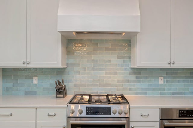 kitchen featuring white cabinets, oven, stainless steel range, and tasteful backsplash