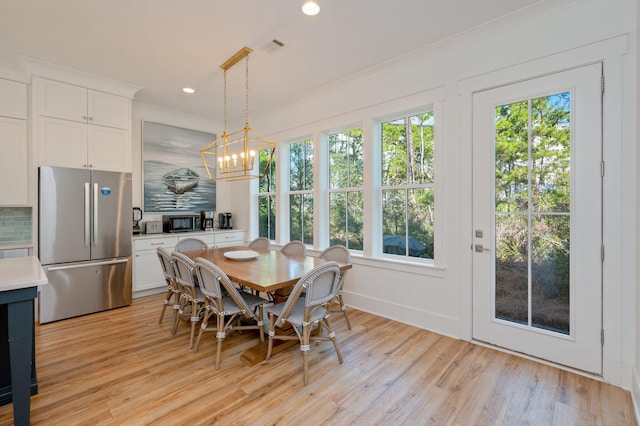 dining space featuring light hardwood / wood-style floors, ornamental molding, and an inviting chandelier