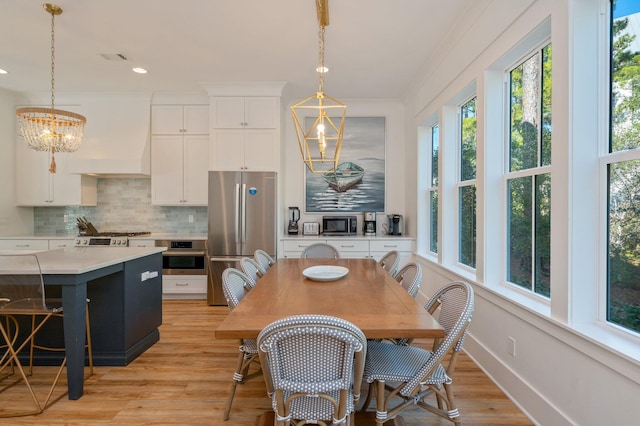 dining area featuring crown molding, light hardwood / wood-style flooring, and an inviting chandelier