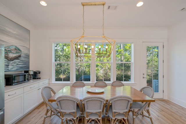 dining space with crown molding, light hardwood / wood-style flooring, and a chandelier