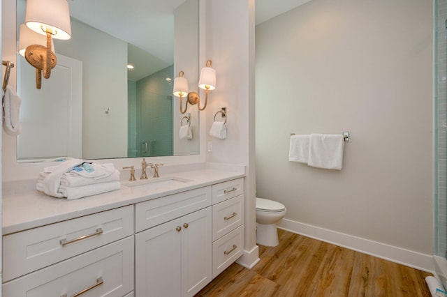 bathroom featuring hardwood / wood-style flooring, toilet, vanity, and walk in shower