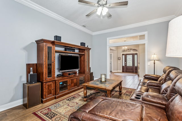 living room featuring ornamental molding, ceiling fan with notable chandelier, and light wood-type flooring