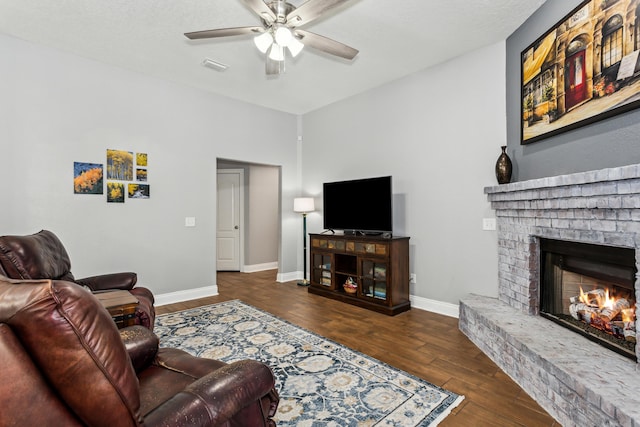 living room featuring dark hardwood / wood-style flooring, ceiling fan, and a fireplace