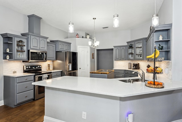 kitchen featuring pendant lighting, tasteful backsplash, stainless steel appliances, and kitchen peninsula