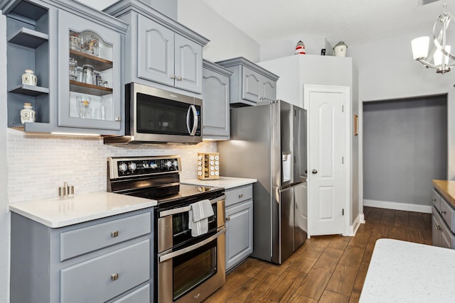 kitchen with stainless steel appliances, gray cabinets, pendant lighting, and decorative backsplash