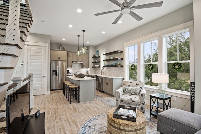 living room featuring ceiling fan, sink, and light hardwood / wood-style floors