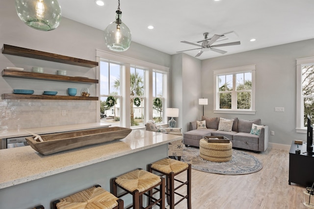 living room with light hardwood / wood-style flooring, plenty of natural light, and ceiling fan