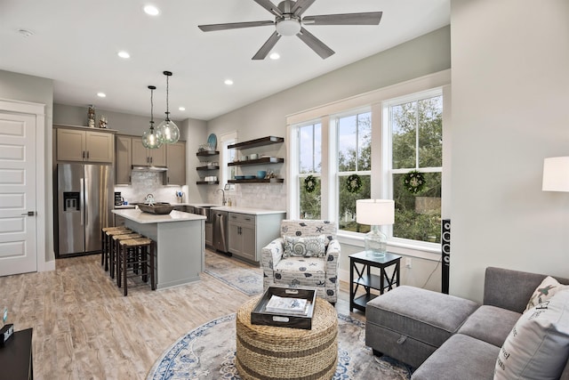 living room featuring ceiling fan, light hardwood / wood-style flooring, and sink