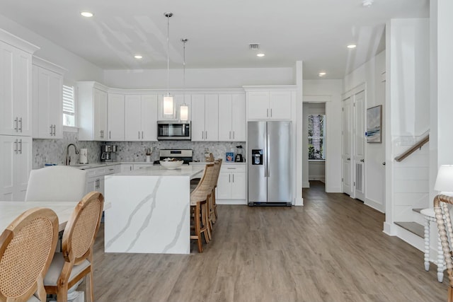 kitchen with white cabinetry, a center island, decorative light fixtures, and appliances with stainless steel finishes