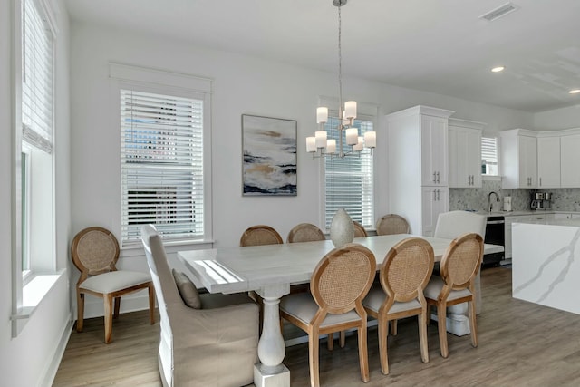 dining room featuring a healthy amount of sunlight, light hardwood / wood-style flooring, a chandelier, and sink