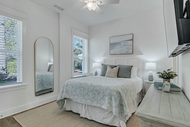 bedroom featuring multiple windows, ceiling fan, and hardwood / wood-style floors