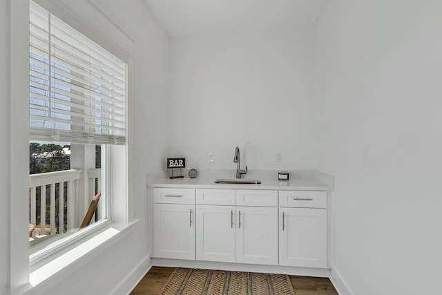 bar with white cabinets, sink, and dark wood-type flooring