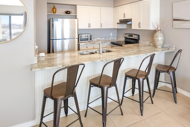 kitchen with light stone counters, appliances with stainless steel finishes, white cabinetry, and sink