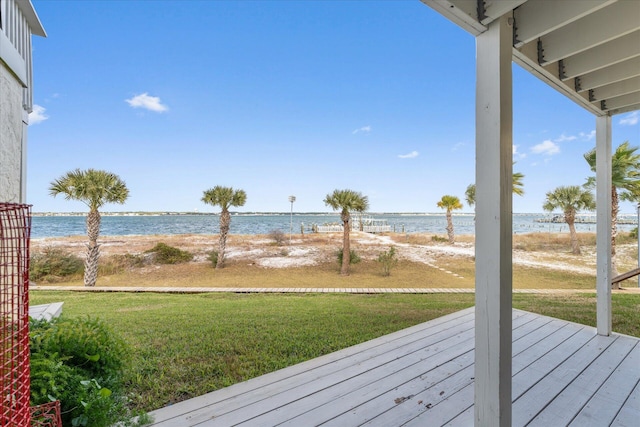 wooden terrace featuring a beach view, a yard, and a water view