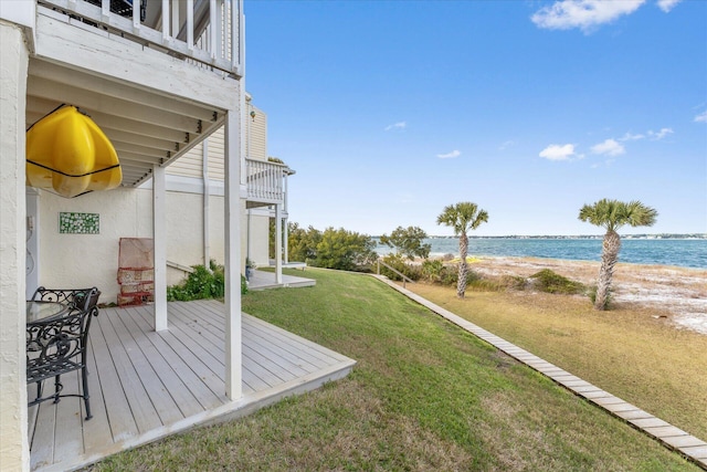 view of yard with a balcony, a deck with water view, and a beach view