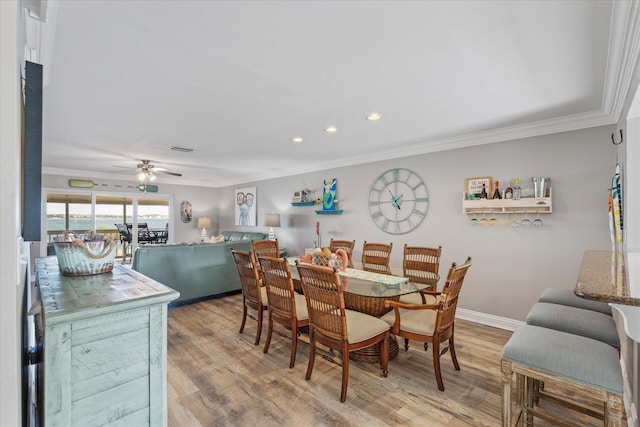 dining area with ceiling fan, light wood-type flooring, and ornamental molding